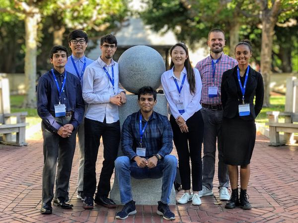 HEATlab students wearing conference badges, posed around a stone sphere sculpture