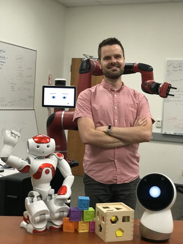 Jim with the lab's robots: a Sawyer robot arm, a NAO humanoid, and a Jibo social robot